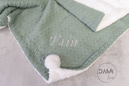 Personalised knitted baby blanket with white sherpa lining and 2 pom-poms.