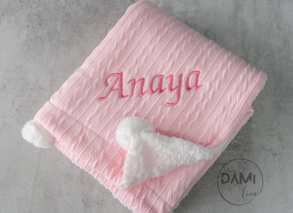 Personalised knitted baby blanket with white sherpa lining and 2 pom-poms.