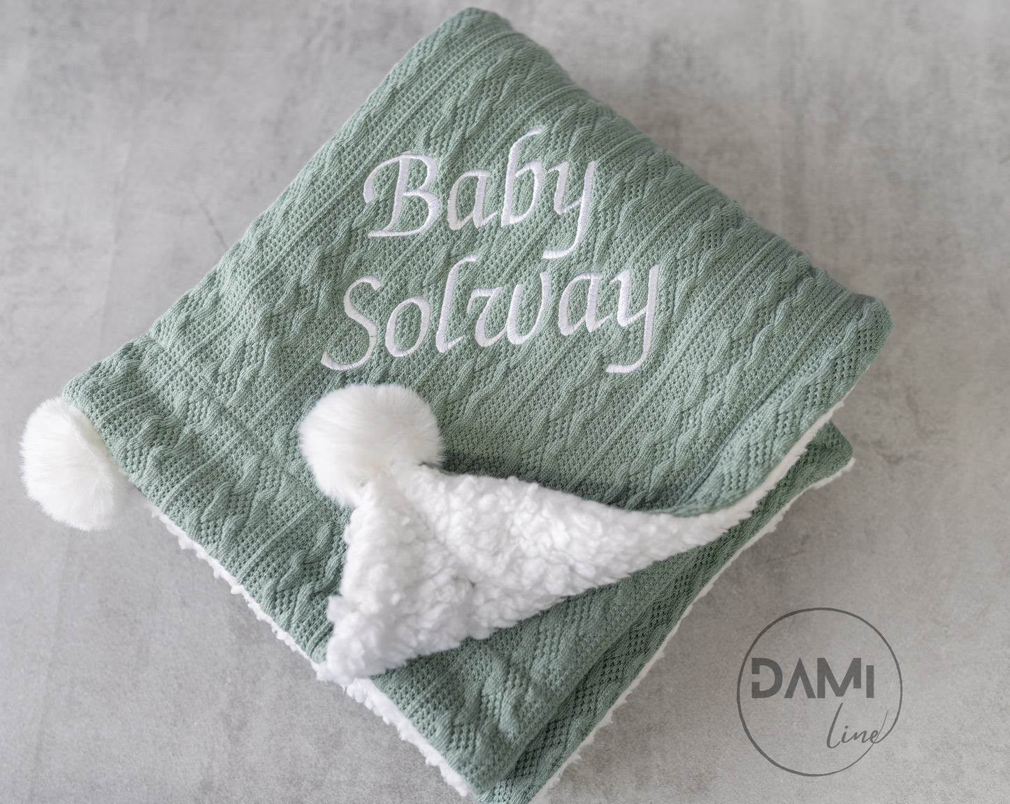 Personalised knitted baby blanket with white sherpa lining and 2 pom-poms.