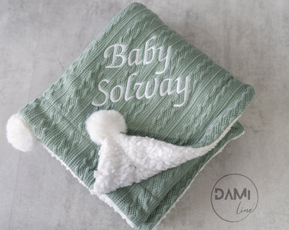 Personalised knitted baby blanket with white sherpa lining and 2 pom-poms.