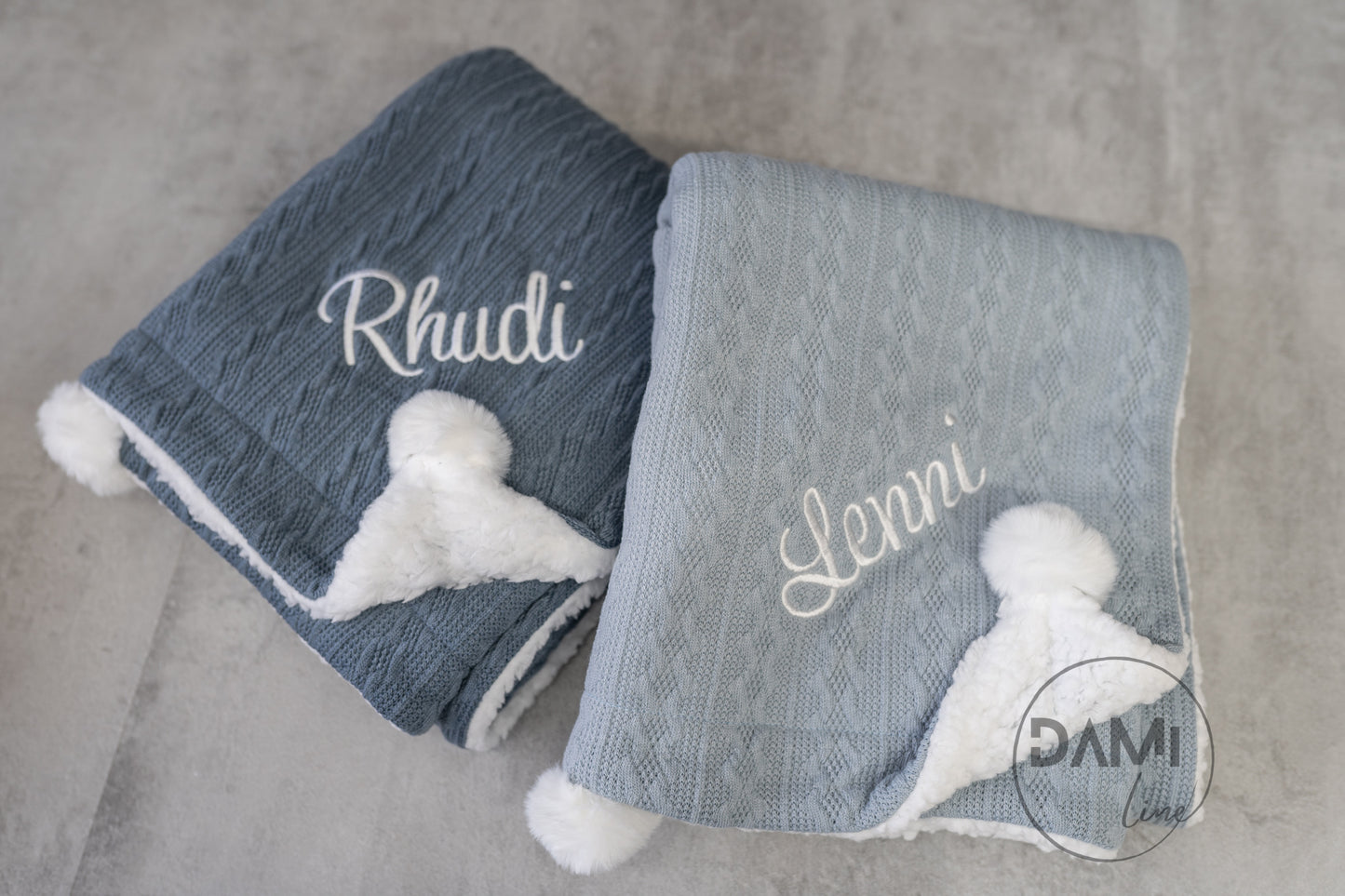 Personalised knitted baby blanket with white sherpa lining and 2 pom-poms.