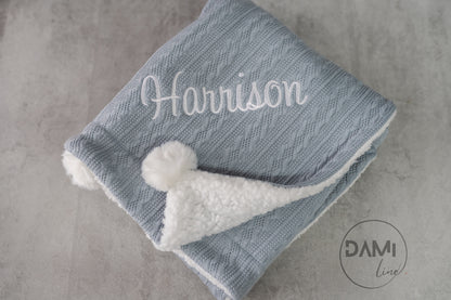 Personalised knitted baby blanket with white sherpa lining and 2 pom-poms.