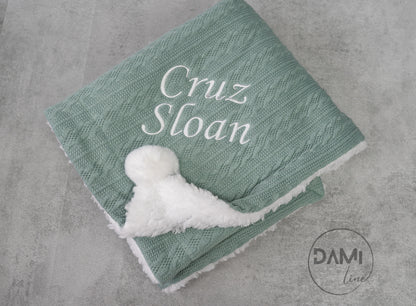 Personalised knitted baby blanket with white sherpa lining and 2 pom-poms.