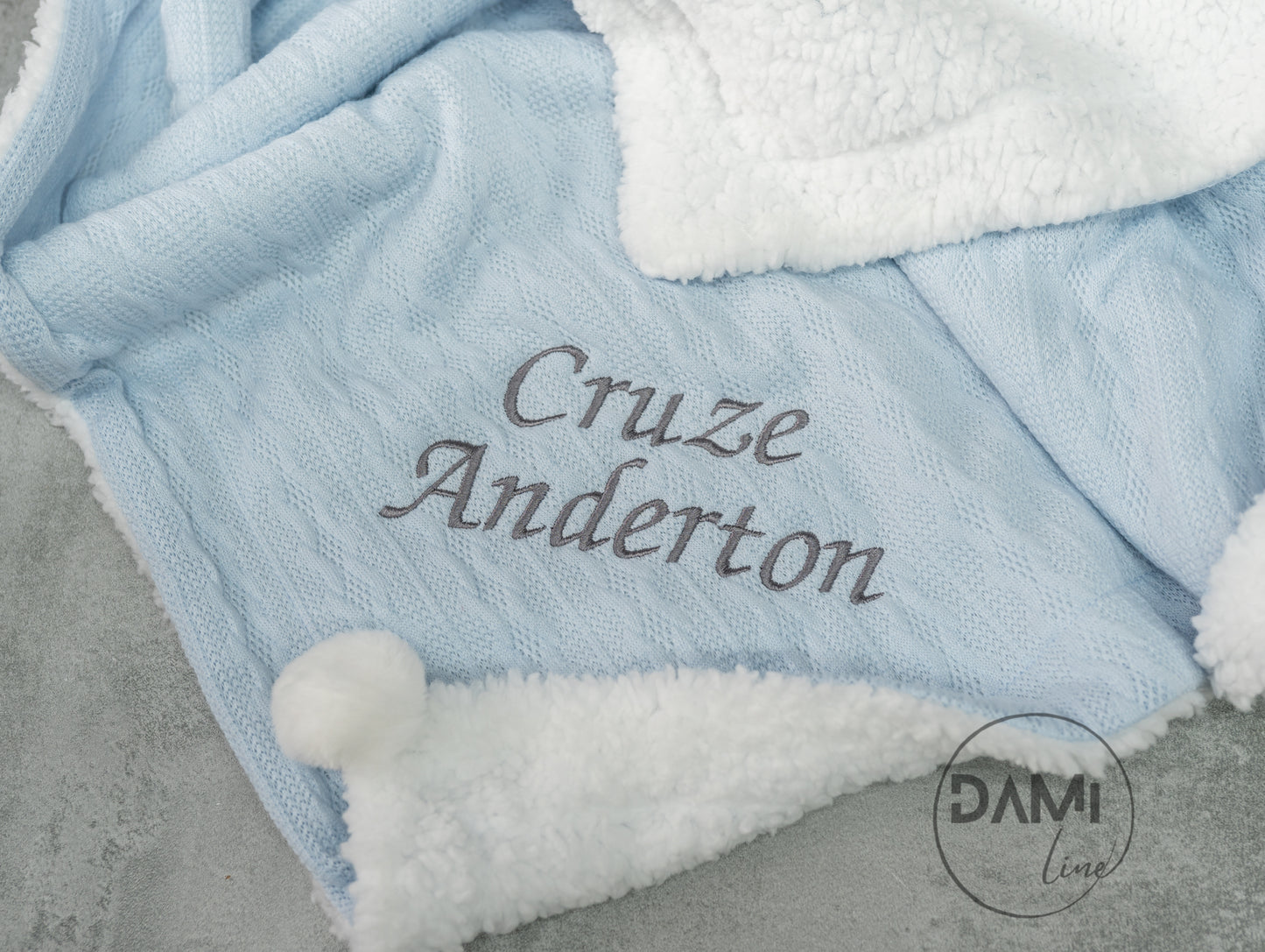 Personalised knitted baby blanket with sherpa lining and 2 pom-poms.