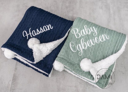 Personalised knitted baby blanket with white sherpa lining and 2 pom-poms.