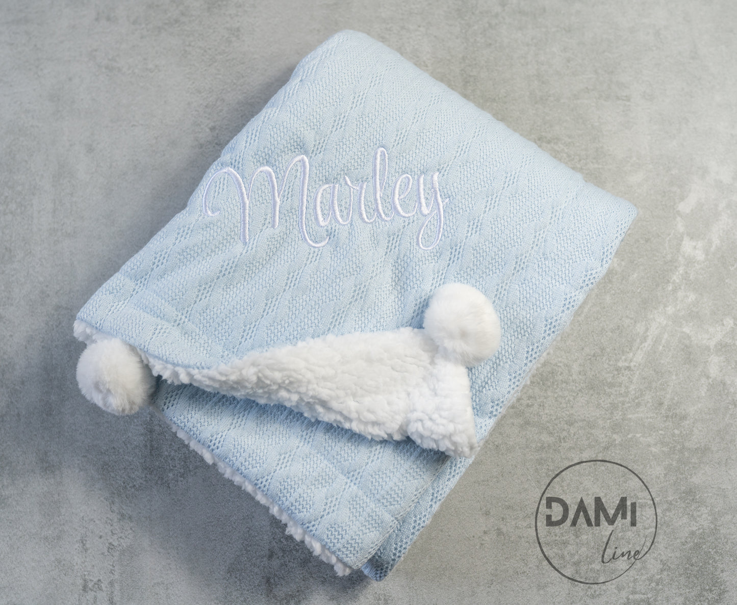 Personalised knitted baby blanket with sherpa lining and 2 pom-poms.