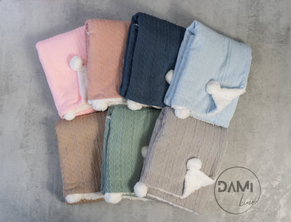 Personalised knitted baby blanket with white sherpa lining and 2 pom-poms.